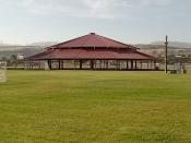 A large Dance Pavilion with a red roof in a Park.